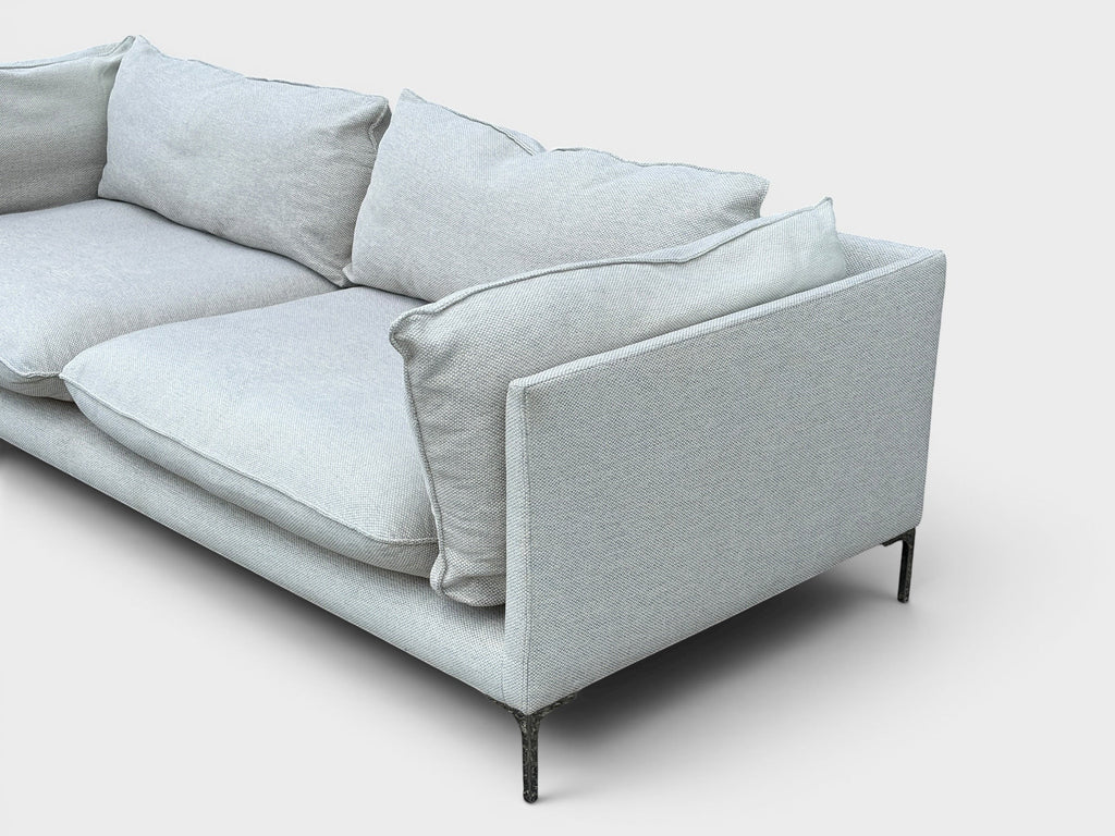 RehomedHere light grey three-seater sofa with plush cushions and slim stainless steel legs, modern design.