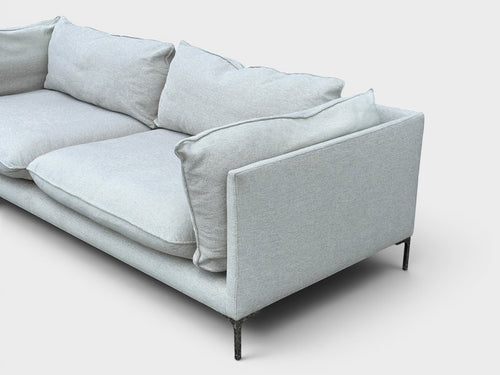 RehomedHere light grey three-seater sofa with plush cushions and slim stainless steel legs, modern design.
