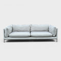 RehomedHere light grey three-seater sofa with plush cushions and slim stainless steel legs, modern design.